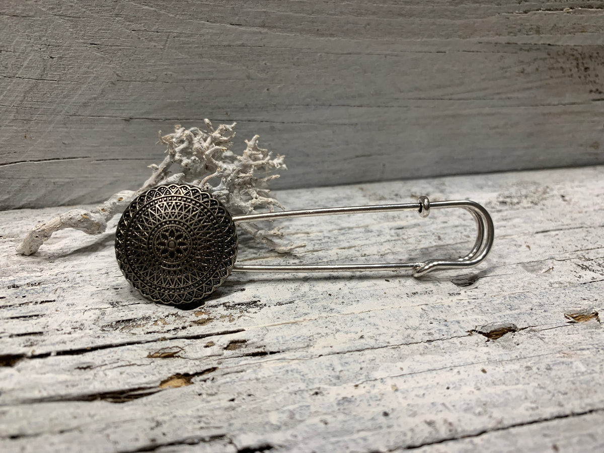 Ponchonadel in Altsilber-Optik in Seitenansicht auf grauem Holz