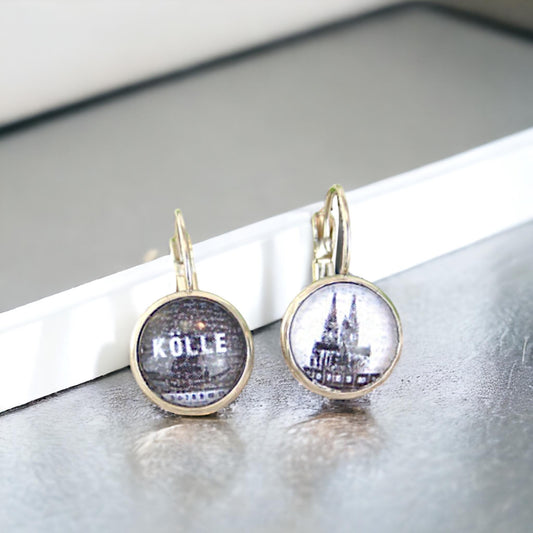 Ohrhänger mit Brisur, ein Motiv mit Schriftzug Kölle, eines mit Kölner Dom, auf hellem Untergrund