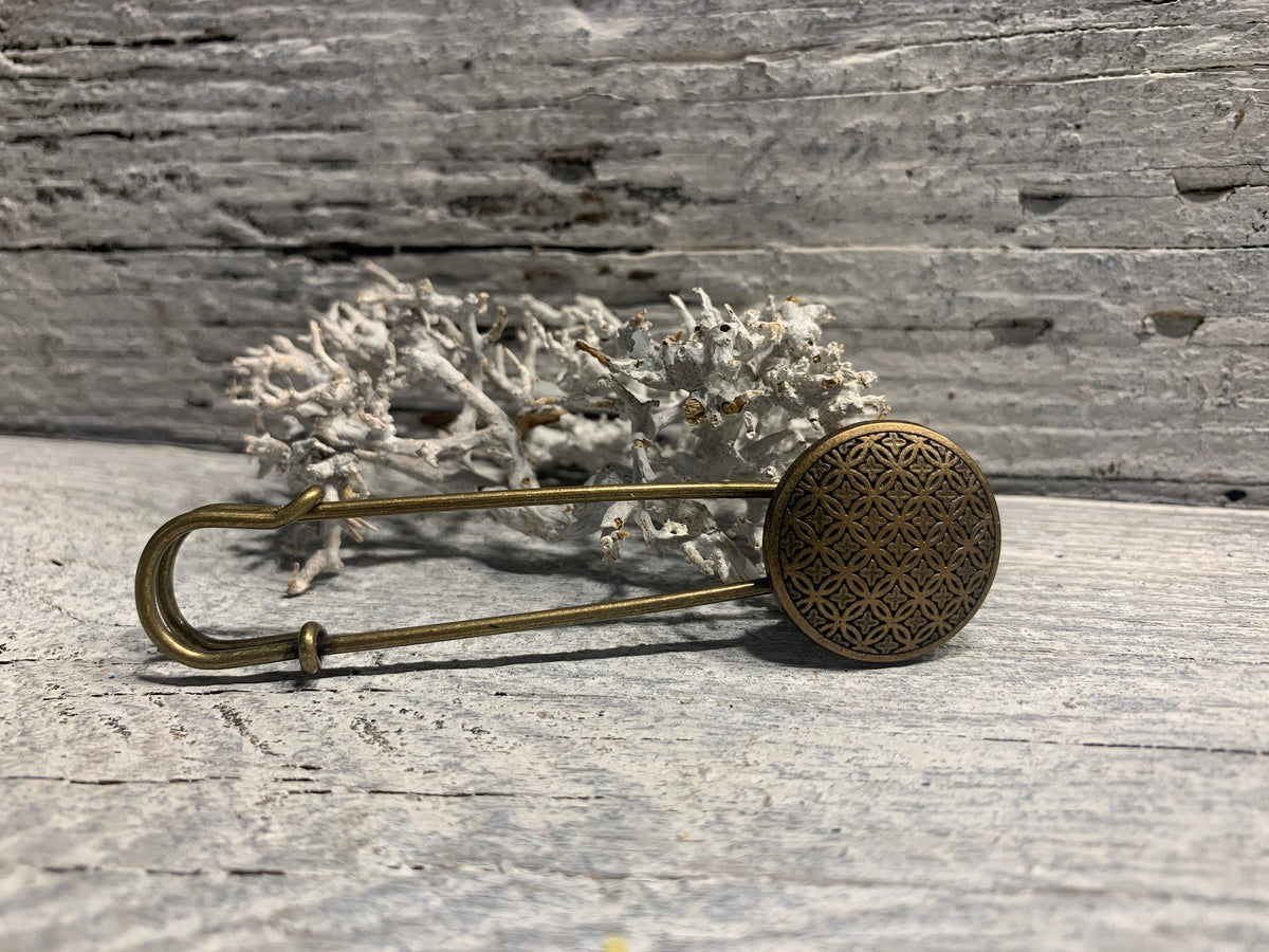 Bronzefarbene Ponchonadel auf hellem Holz