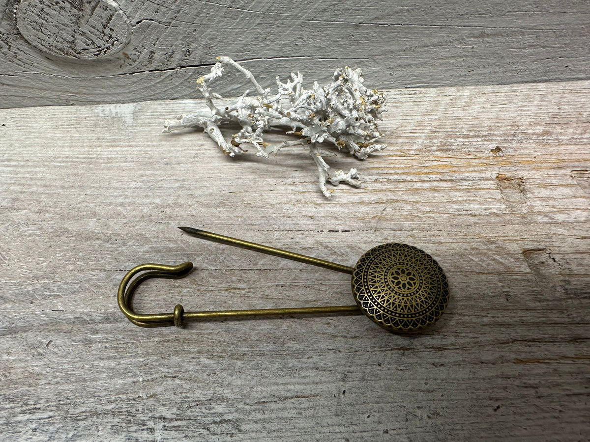 Geöffnete Ponchonadel mit bronzefarbenem Ornament