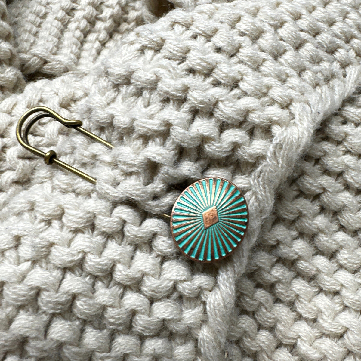 Ponchonadel verschließt eine cremeweiße Strickjacke