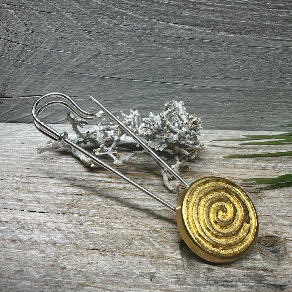Ponchonadel mit Spirale vor Trockenflechte auf grauem Holz