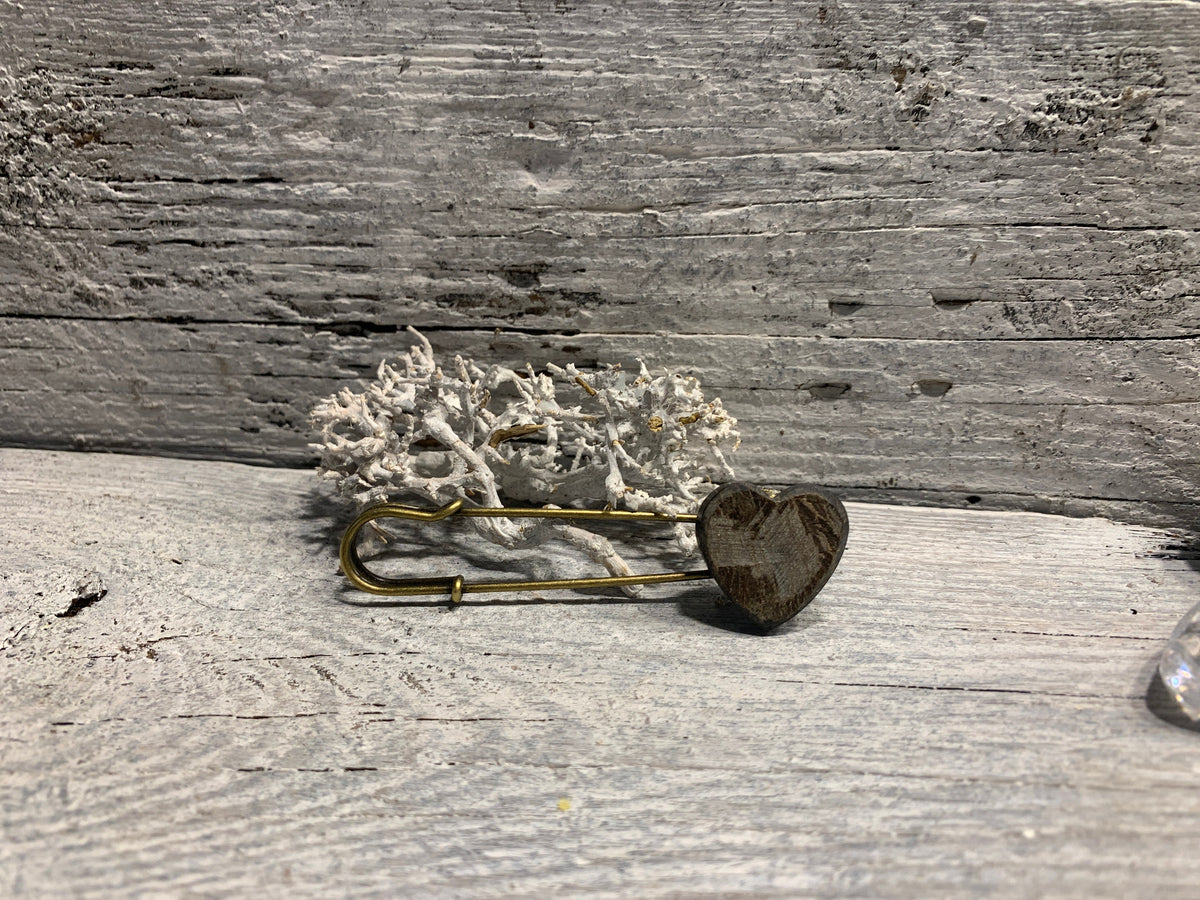 Ponchonadel mit Herz aus Horn in Seitenansicht auf grauem Holz