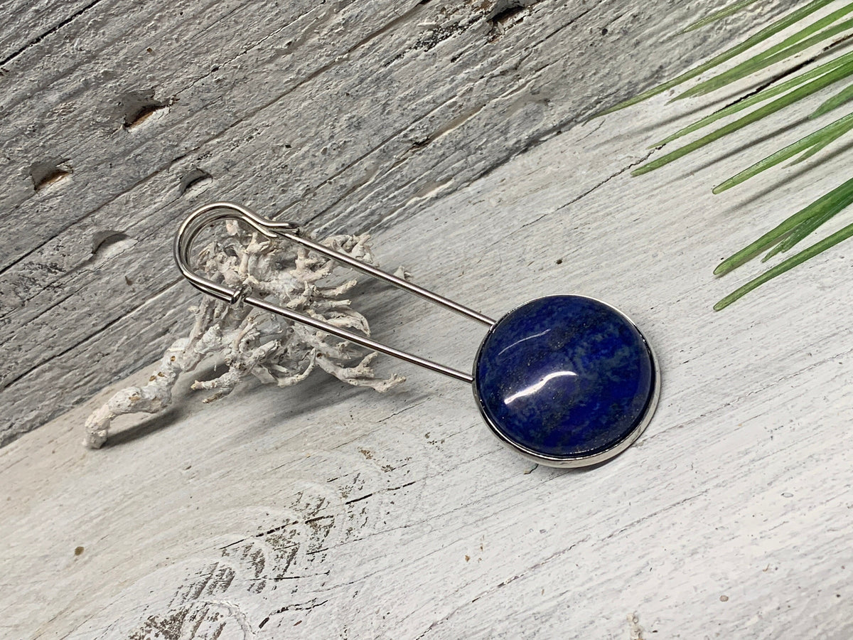 Ponchonadel mit Lapis Lazuli auf weiß verwittertem Holz neben Trockenflechte