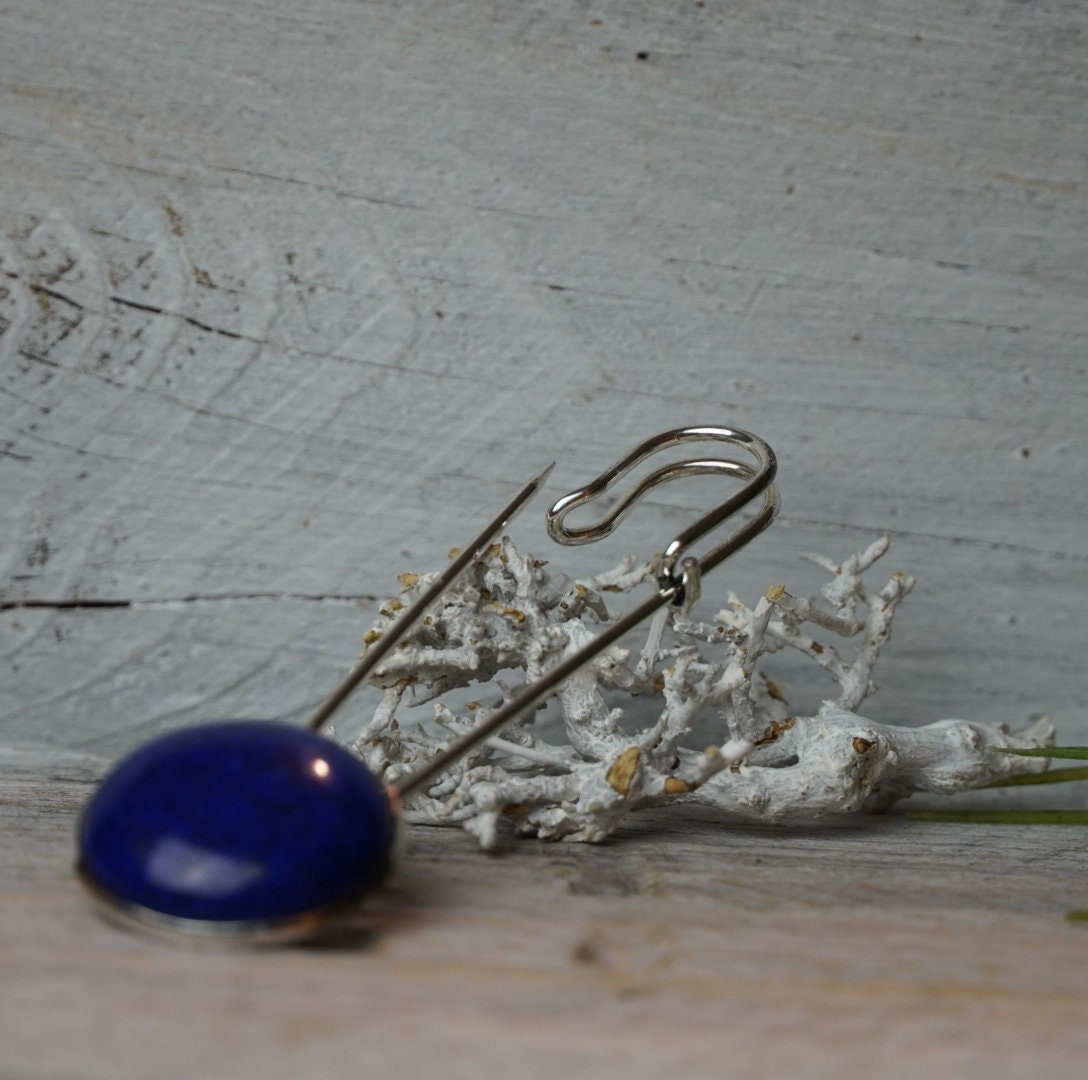Ponchonadel mit Lapis Lazuli liegend vor Trockenflechte auf grauem Holz