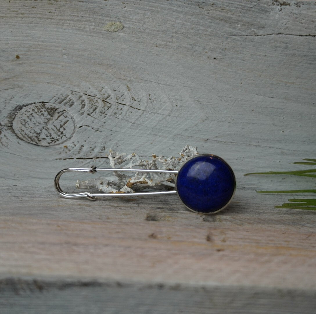 Ponchonadel mit Lapis Lazuli auf grauem Holzuntergrund