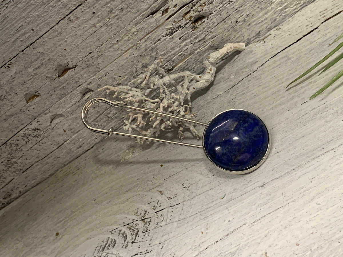 Ponchonadel mit Lapis Lazuli schräg auf weiß gekalktem Holz mit Trockenflechte