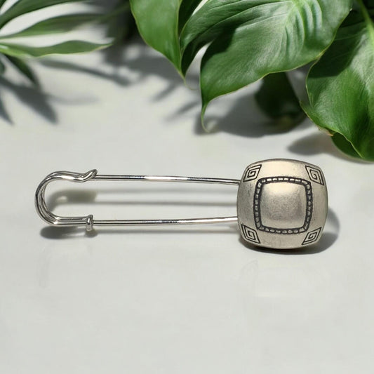 Ponchonadel mit quadratischem Element in Altsilber-Optik vor grünen Blättern