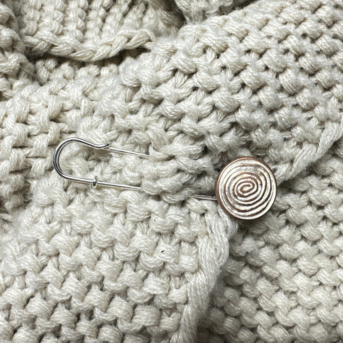 Schneckenspirale als Verschluss an hellem Strick
