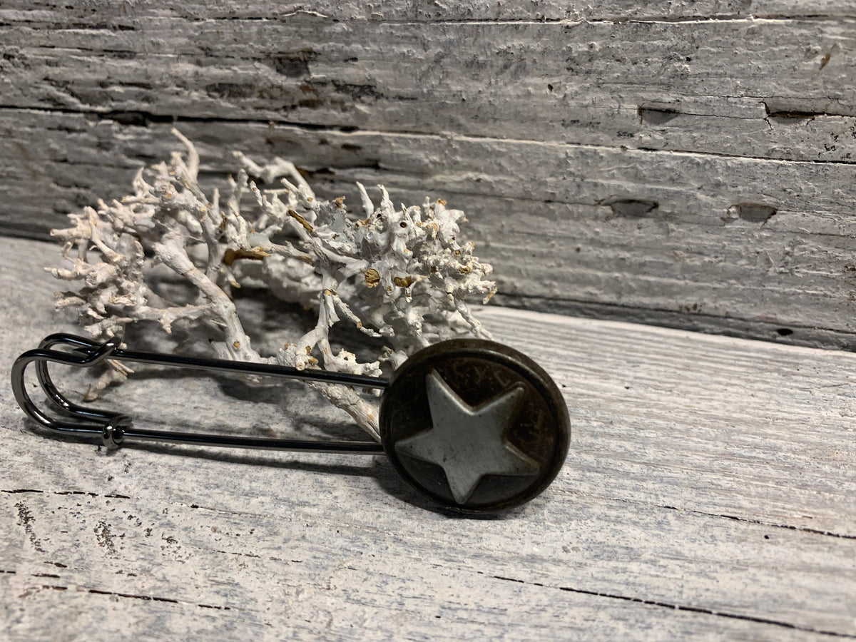 Schwarze Ponchonadel mit Stern in Seitenansicht auf grauem Holz